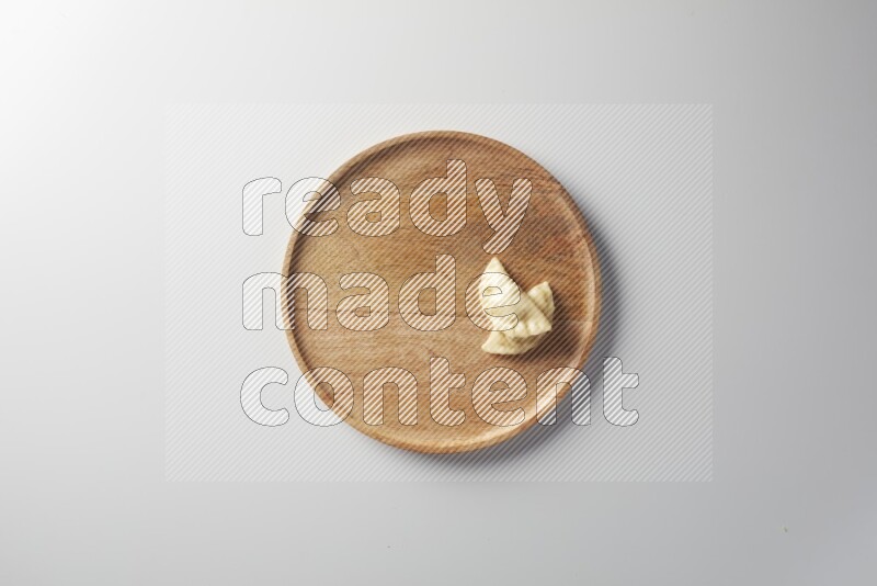 Two Sambosas on a wooden round plate on a white background