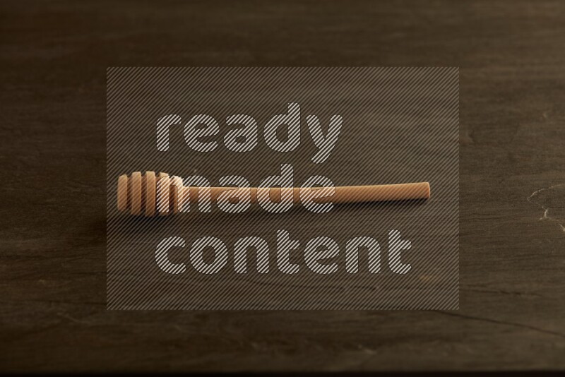 Wooden honey dipper on black slate background