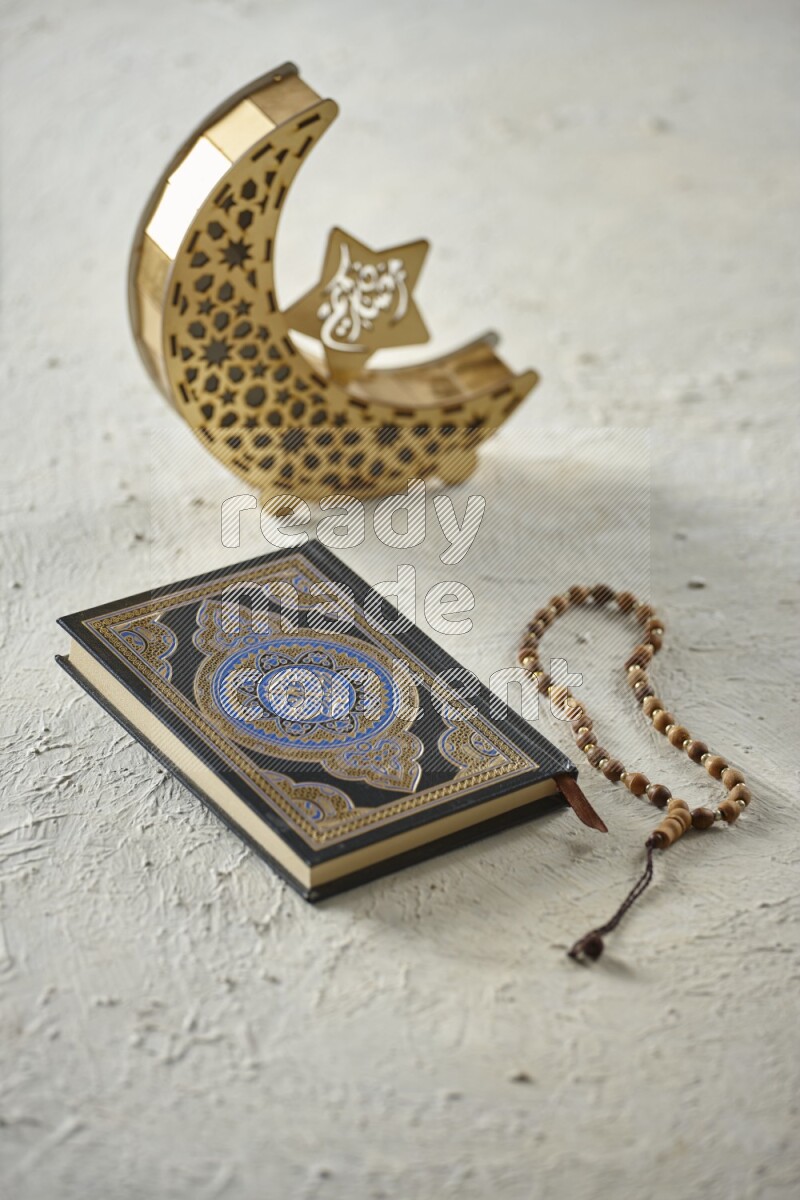 A wooden golden crescent lantern with different drinks, dates, nuts, prayer beads and quran on white background