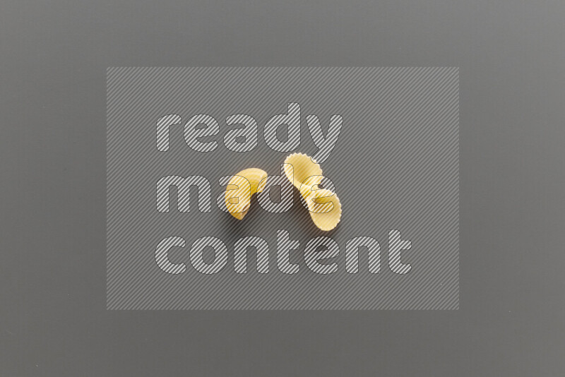 Elbow pasta with other types of pasta on grey background