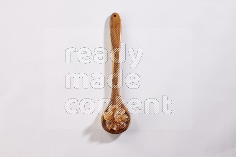 A wooden ladle filled with gum arabic on white flooring