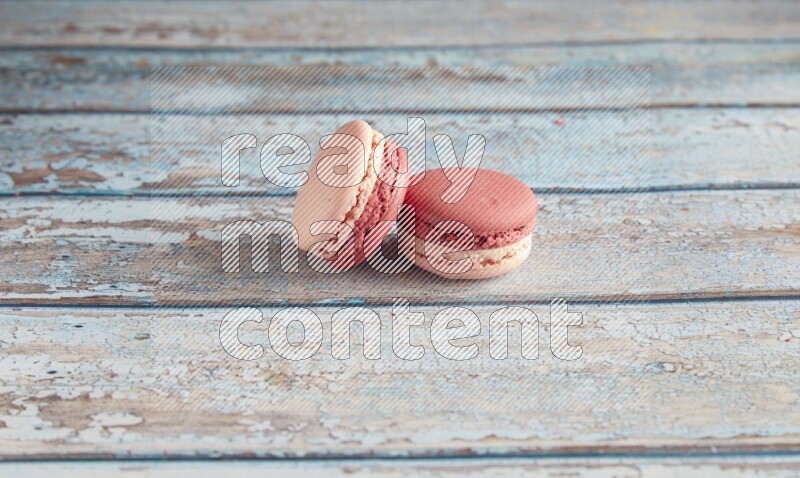 45º Shot of two Pink Litchi Raspberry macarons on light blue wooden background