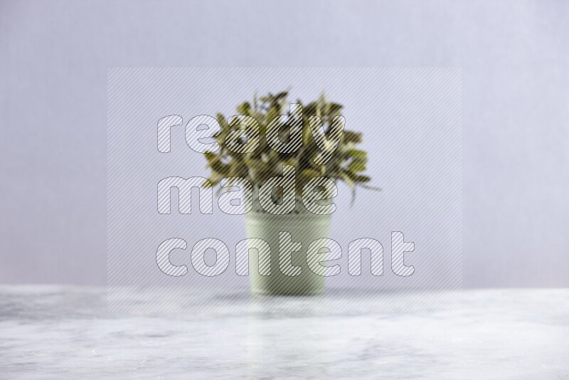 Artificial plant in green decorative pot on grey marble background