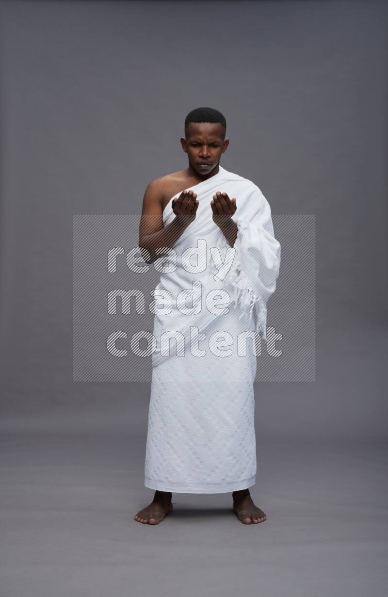A man wearing Ehram Standing dua'a on gray background