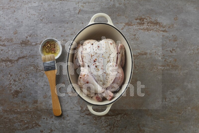 whole raw chicken on in a white ceramic pot direct on a rustic grey background