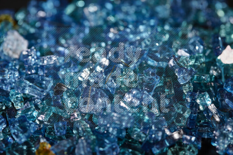 Transparent blue fragments of glass scattered on a black background