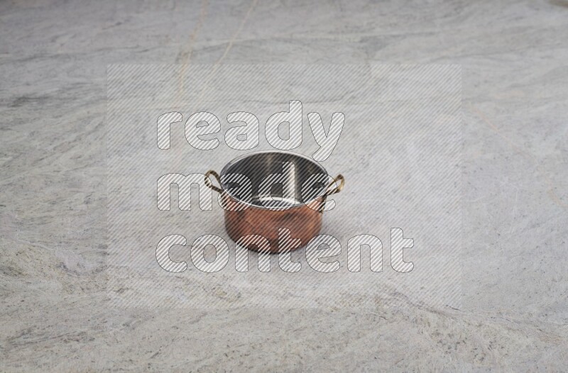 A small copper pot on grey marble background