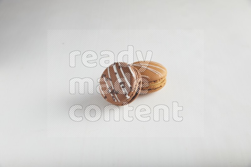 45º Shot of of two assorted Brown Irish Cream, and Brown white Chocolate Caramel macarons on white background
