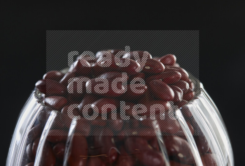 Red kidney beans in a glass jar on black background