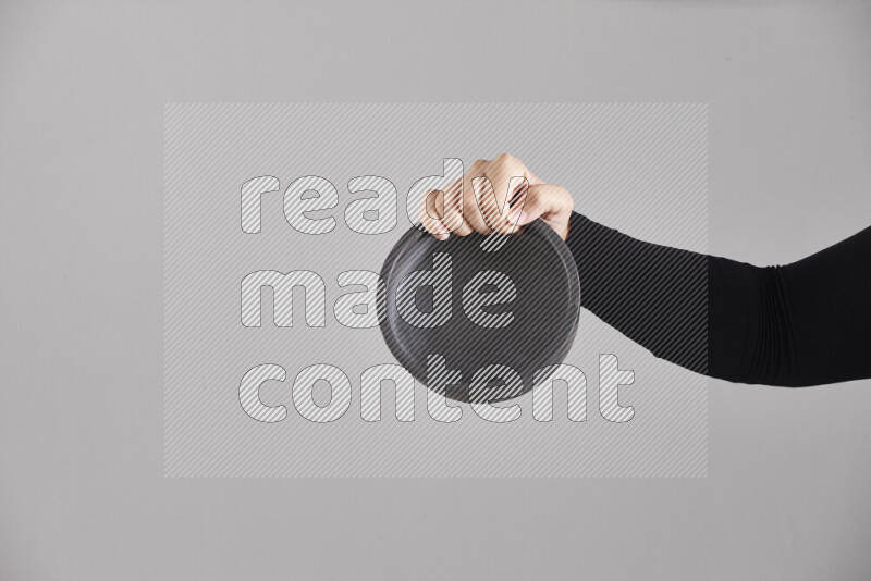 A woman in black abaya holding different pottery essentials in different positions