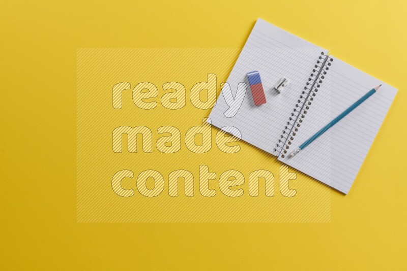 دفتر مفتوح مع مستلزمات مدرسية مختلفة على خلفية صفراء