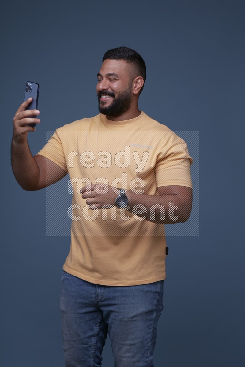 A man Texting on his phone in Blue Background wearing Orange T-shirt