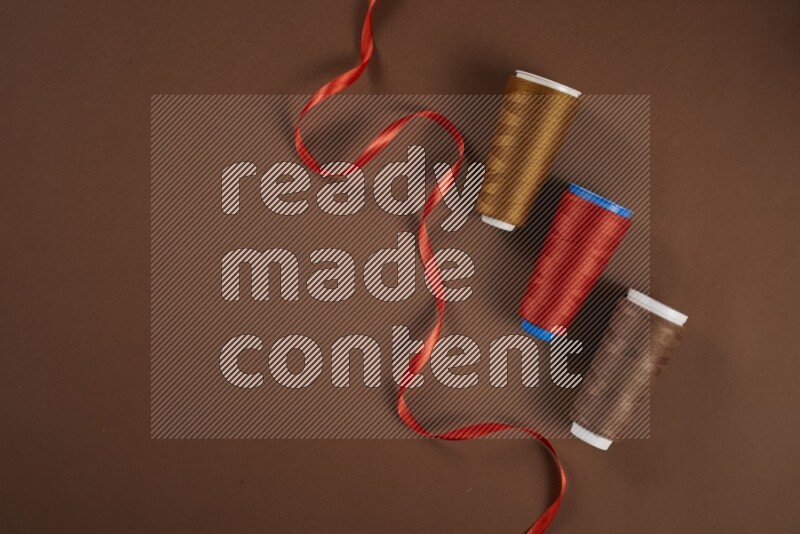 مجموعة من أدوات الخياطة والتفصيل حمراء اللون على خلفية بنية