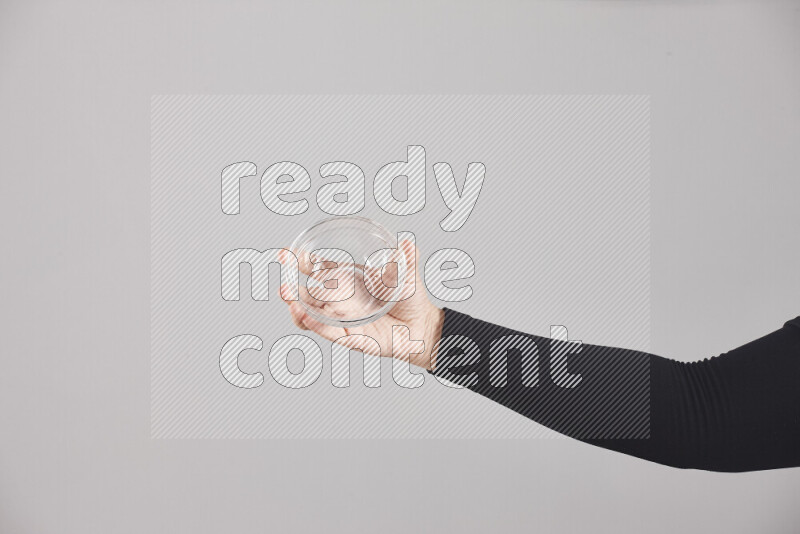 A woman in black abaya holding different glassware in different positions