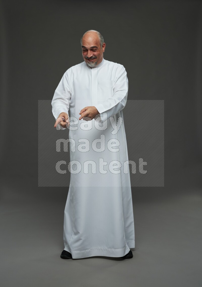 Saudi man without shomag Standing Interacting with the camera on gray background