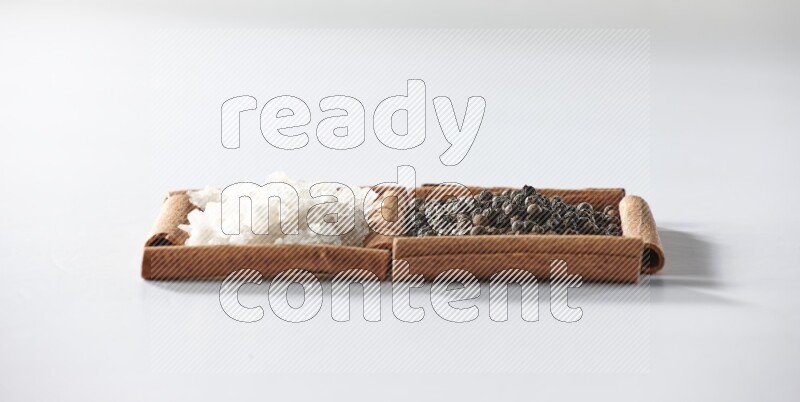 2 squares of cinnamon sticks full of black pepper and white salt on white flooring