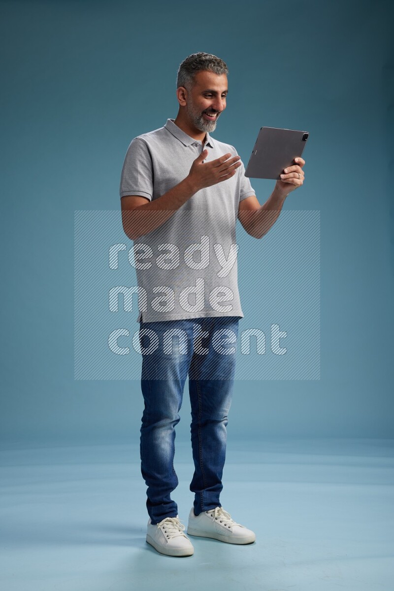 Man Standing working on tablet on blue background