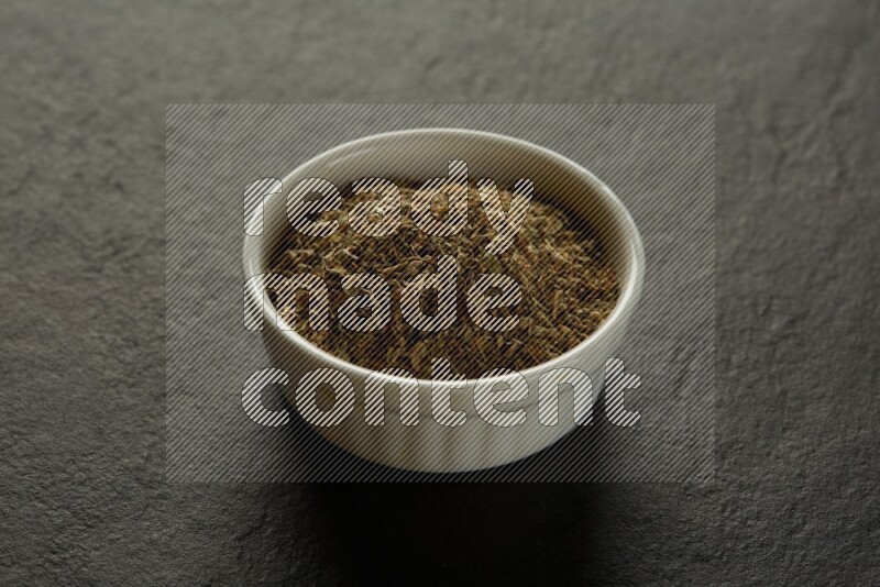 wooden round sauce bowl filled with herbs on grey textured countertop