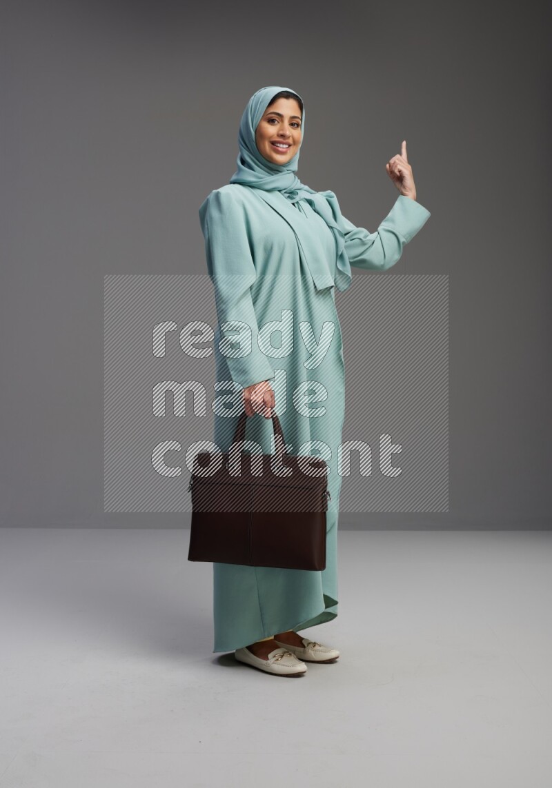 Saudi Woman wearing Abaya standing holding bag on Gray background