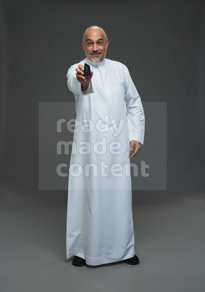 Saudi man without shomag Standing holding car key on gray background