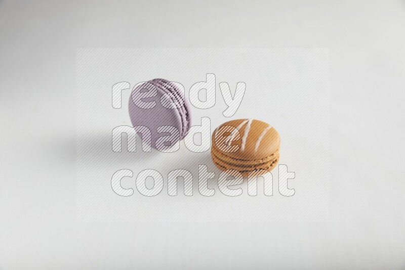 45º Shot of of two assorted Brown Irish Cream, and Purple Blueberry macarons on white background