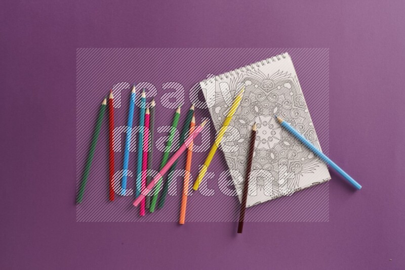 A coloring book with coloring pens on purple background