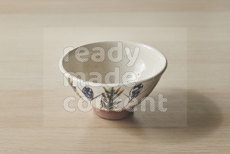 A decorative pottery bowl on light wooden background