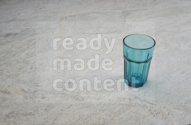 A turquoise glass cup on grey marble background