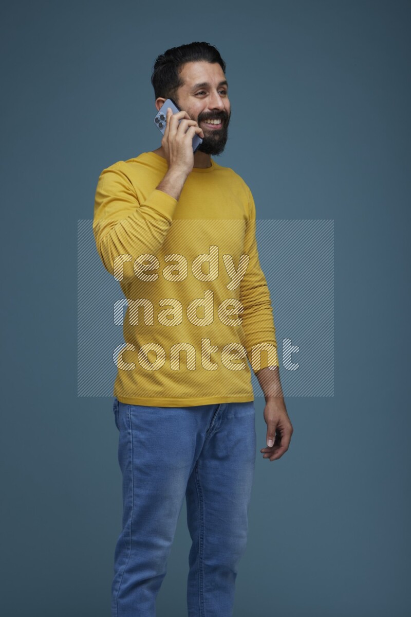 A man having a calling in a blue background wearing a yellow shirt
