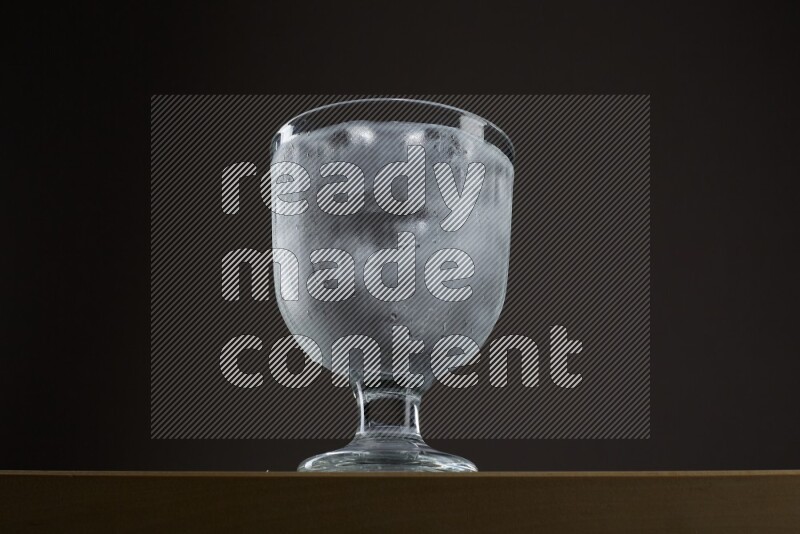 Low angle shot of a glass of water and ice on grey background