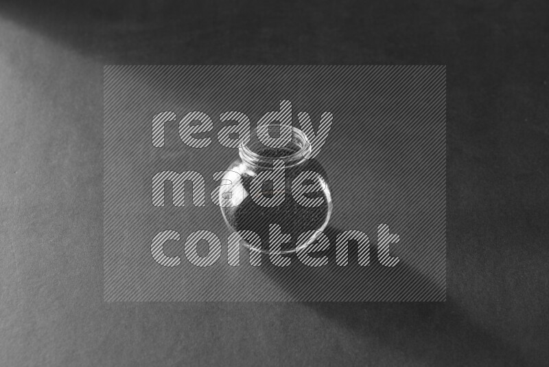 A glass spice jar full of black seeds on black flooring