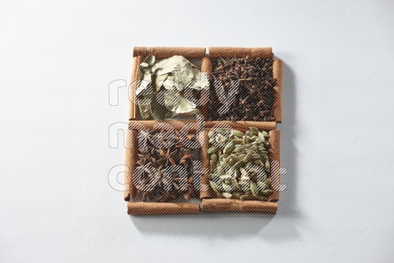 4 squares of cinnamon sticks full of cardamom, star anise, cloves and bay laurel leaves on white flooring