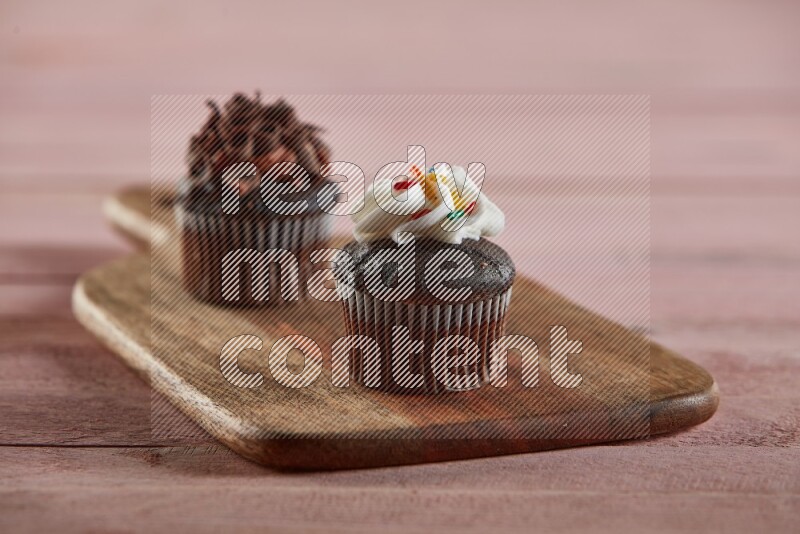 Chocolate mini cupcake topped with cream on a wooden board