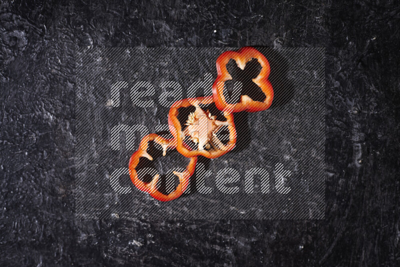 Red bell pepper slices on black background