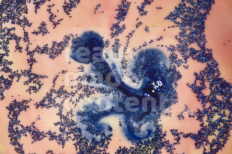 A close-up of sparkling blue glitter scattered on swirling blue and orange background