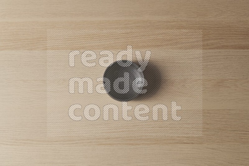 A black pottery bowl on light wooden background