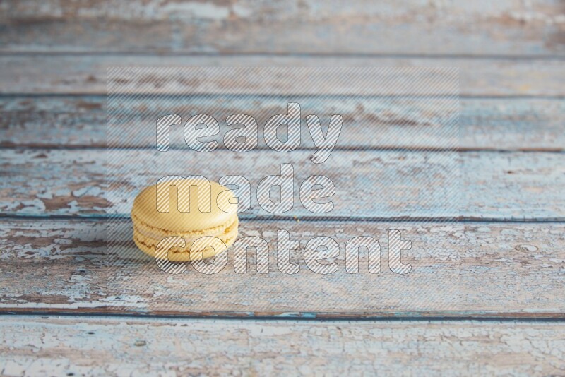 45º Shot of Yellow Vanilla macaron on light blue wooden background