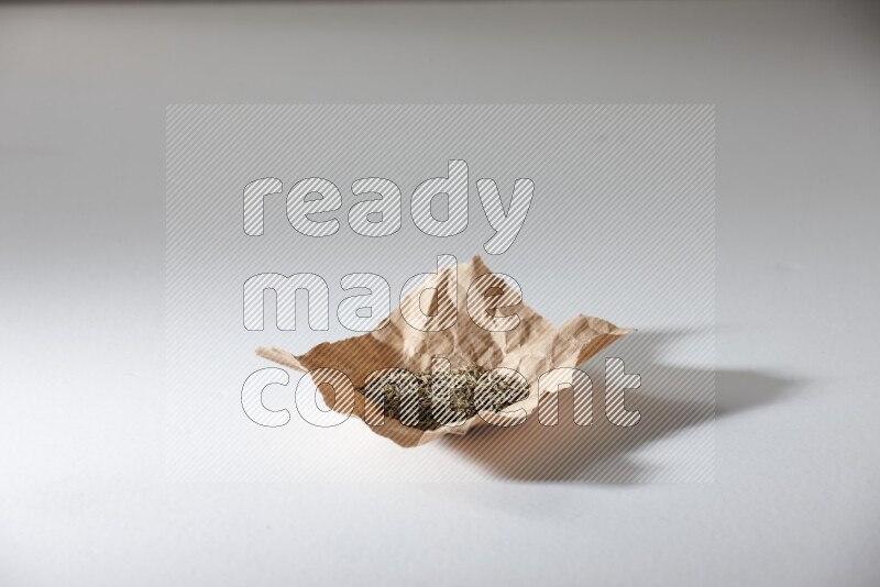 Cumin seeds in a crumpled piece of paper on white flooring