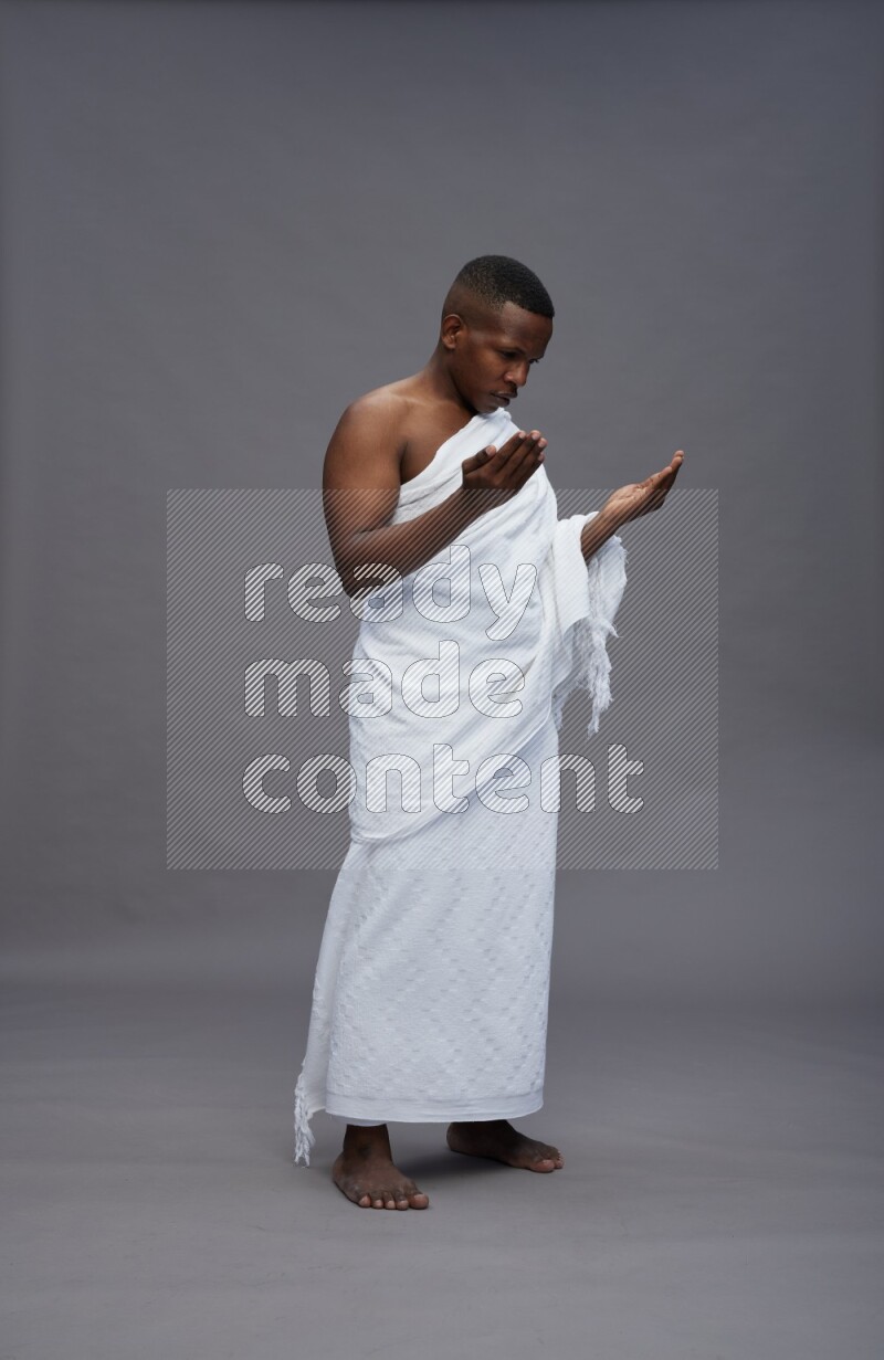 A man wearing Ehram Standing dua'a on gray background