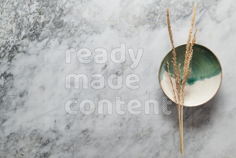 Wheat stalks on multicolored pottery plate on grey marble background