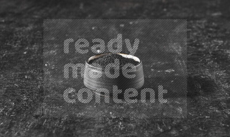 وعاء فخاري أسود ممتلئ ببذور حبة البركة علي خلفية سوداء