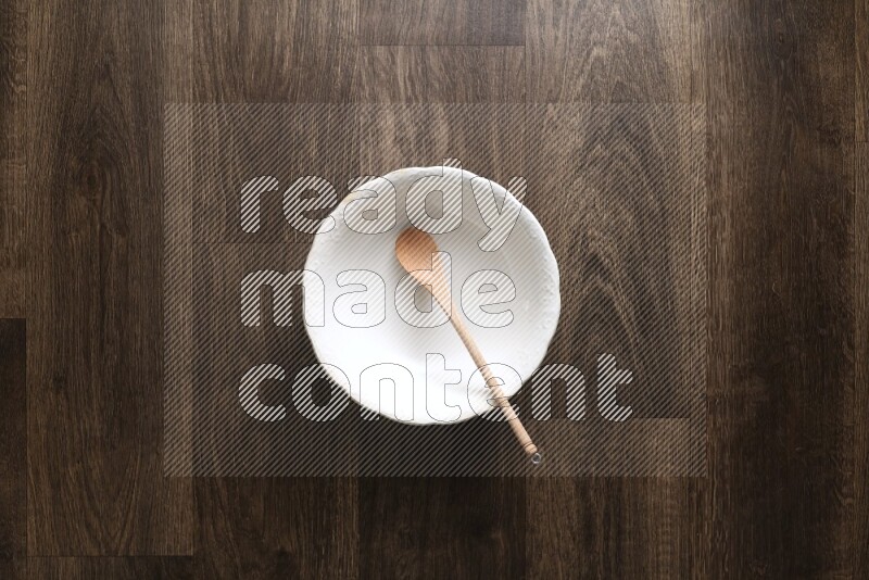 A white bowl full of tuna, colored bell pepper, sour cream, corn, parsley, black pepper powder and sauce, with wooden spoon on wooden background