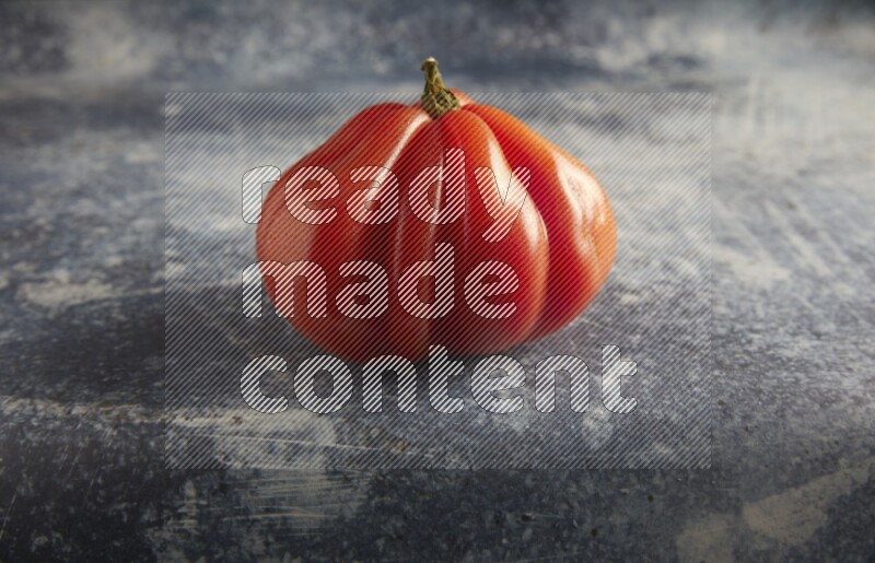 45 degree single heirloom tomato on a textured rustic blue background