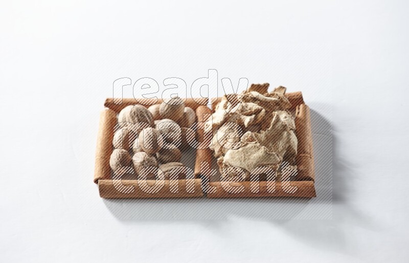 مربعان من أعواد القرفة ممتلئان بالزنجبيل المجفف وجوزة الطيب علي خلفية بيضاء