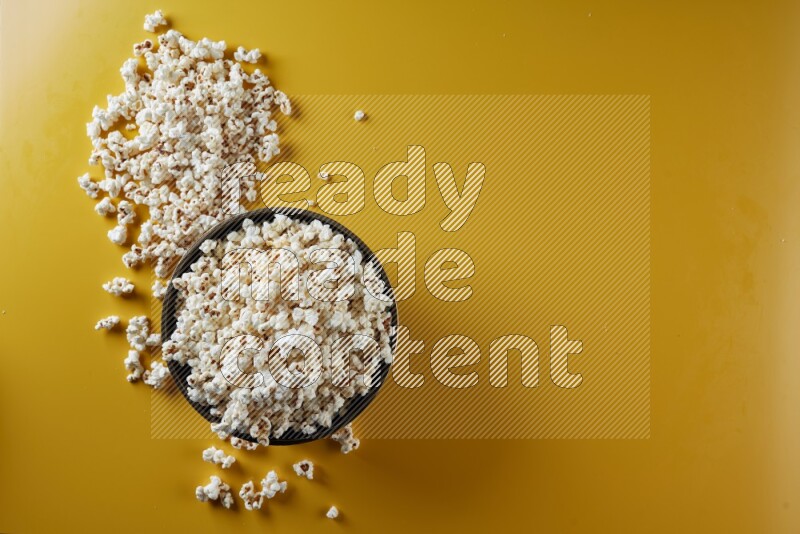 A copper ceramic bowl full of popcorn with popcorn beside it on a yellow background in different angles