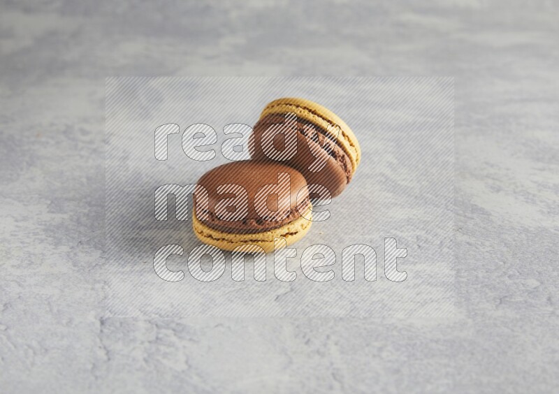 45º Shot of two Yellow and Brown Chai Latte macarons r on white  marble background