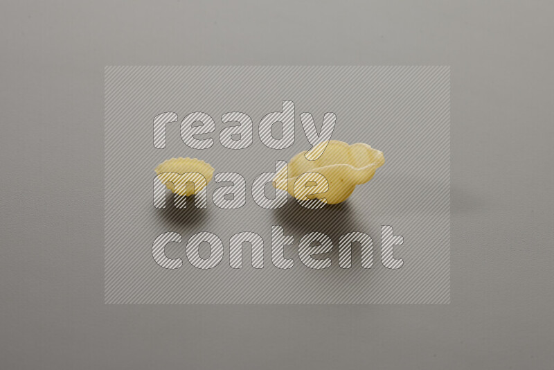 Shells pasta with other types of pasta on grey background