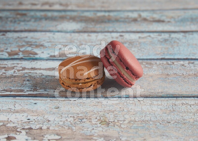 45º Shot of of two assorted Brown Irish Cream, and Red Velvet macarons on light blue background