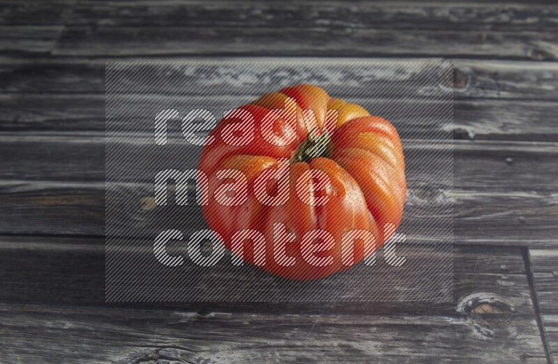 45 degree single heirloom tomato on a textured grey wooden background