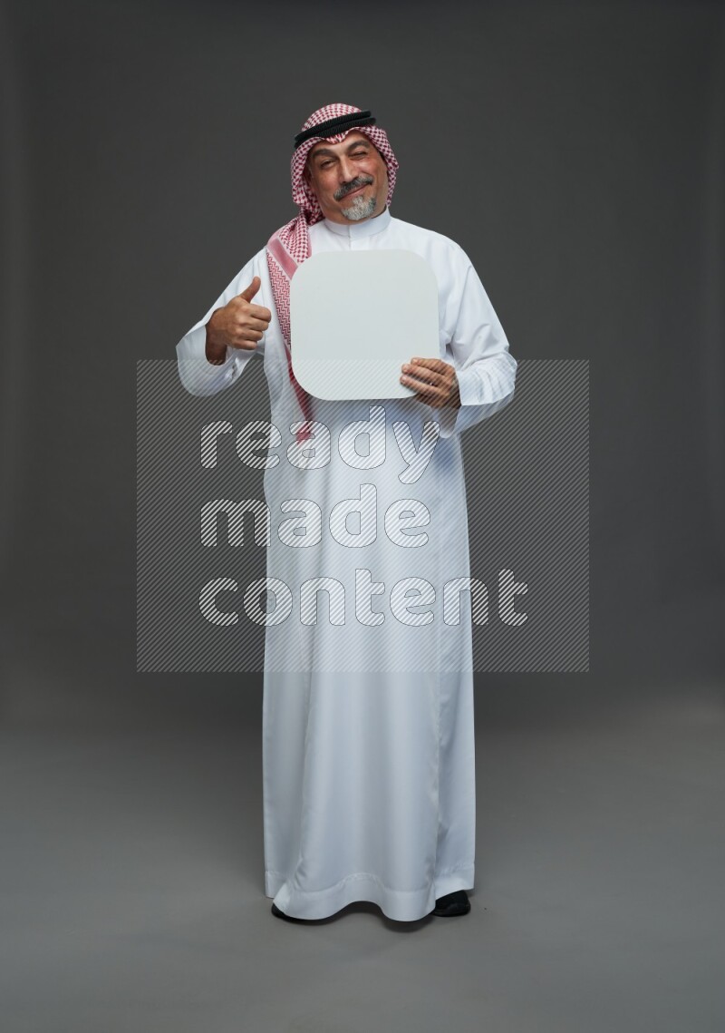 Saudi man with shomag Standing holding social media sing on gray background